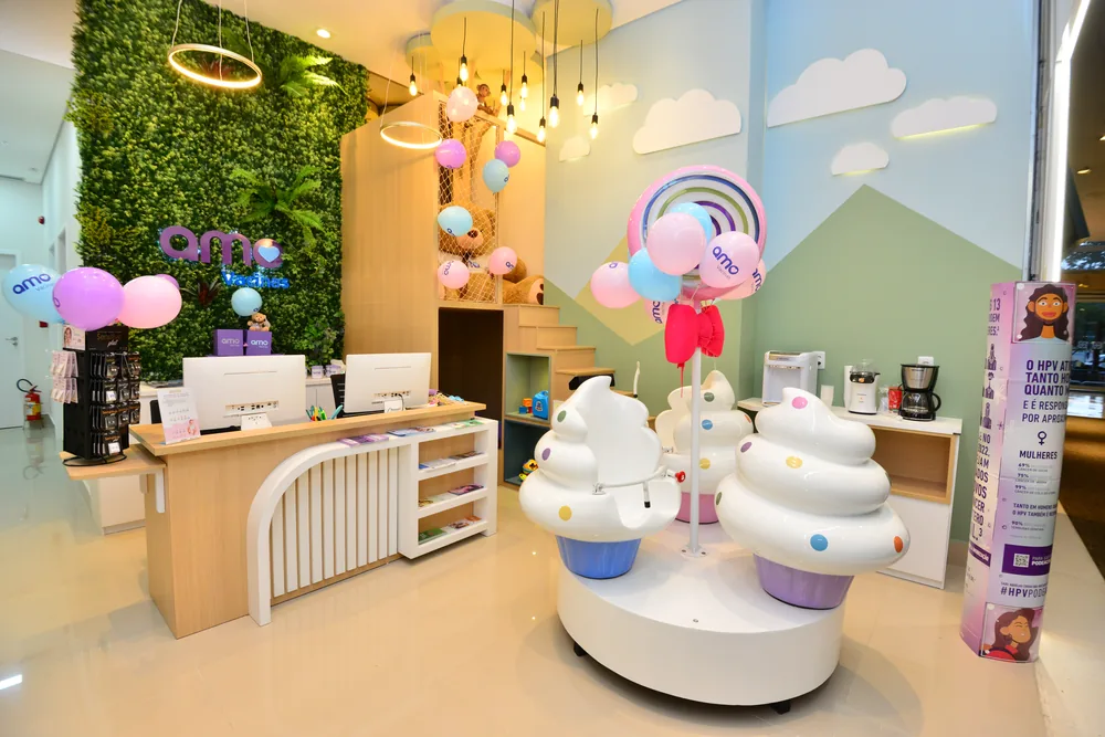 Recepção da Amo Vacinas com jardim vertical, nuvens e cupcakes decorativos